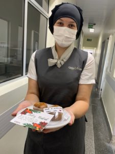 Colaboradora de hospital segurando prato com bolinho e cartão de natal